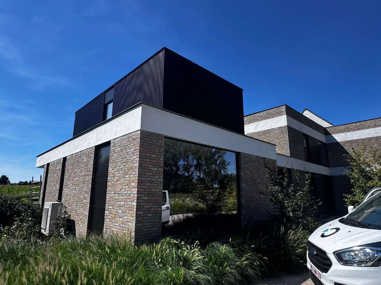 Moderne gevelrealisatie met metselwerk, witte geveldelen en donkere bekleding